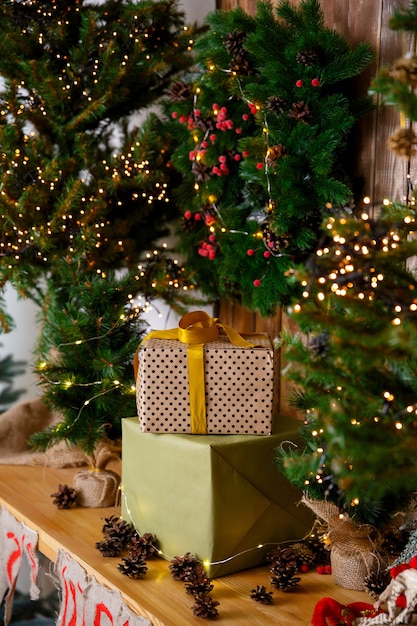 Tarjeta de Navidad Regalos en cajas en envases artesanales de pie cerca del árbol de Año Nuevo en una mesa de madera marrón