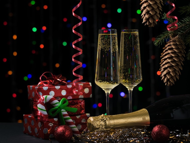 Tarjeta de Navidad con regalos de champán y árbol de Navidad.