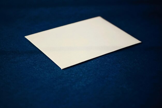 Tarjeta de papel beige en blanco sobre maqueta de identidad de marca de lujo y negocios de fondo azul