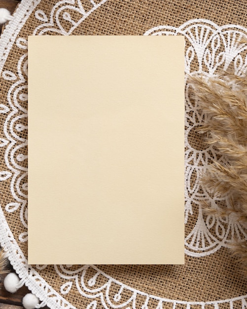 Foto tarjeta de papel en blanco en el mantel de yute bohemio cerca de la vista superior de la hierba de pampas. escena rústica boho con maqueta de tarjeta vertical de saludo o invitación, puesta plana.