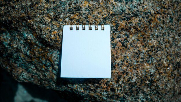 Tarjeta de papel comercial de maqueta en rocas de playa con fondo de textura de piedra