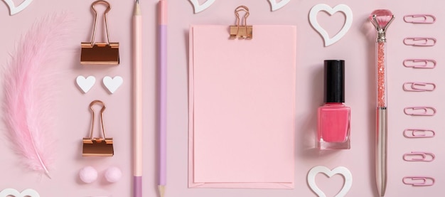 Tarjeta de papel rosa con clip, accesorios de niña escolar y corazones en la vista superior de color rosa pastel, maqueta de tarjeta en blanco. Lugar de trabajo femenino. Conceptos de regreso a la escuela y el día de san valentín