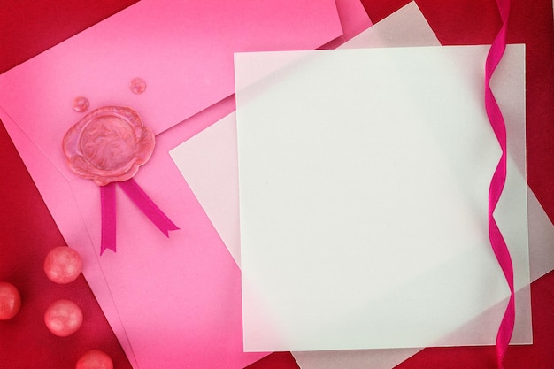 Tarjeta de papel y sobre rosa con sello de lacre