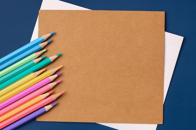 Tarjeta de papel de vista superior con lápiz de color pastel sobre fondo de mesa azul marino