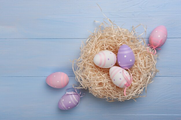 Tarjeta de Pascua feliz con huevos pintados y flores en la mesa de colores, fondo de vacaciones para tu tarjeta. Búsqueda de huevos, espacio de copia