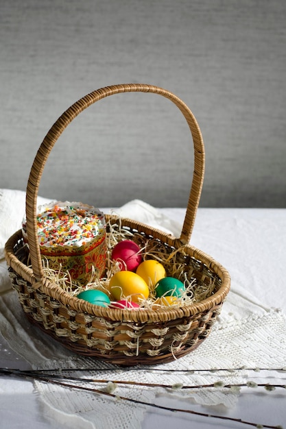 Tarjeta de Pascua Willow ramifica un ícono ortodoxo una canasta con pasteles festivos de Pascua y coloridos huevos rojos amarillos verdes en la mesa con textiles caseros Espacio de primer plano de estilo rústico para copiar