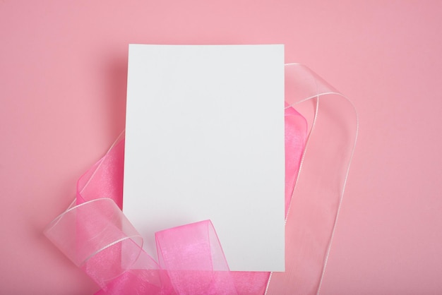 Tarjeta postal en blanco junto a una cinta rosada en fondo rosado Mockup