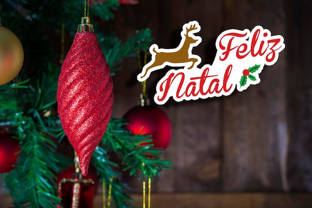 Tarjeta postal de felicitación de Navidad que muestra un adorno rojo de Navidad y un espacio de copia lleno de arte de texto escrito en portugués "Feliz Navidad"