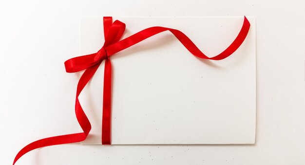 Tarjeta de regalo en blanco arco de cinta roja aislado sobre fondo blanco concepto de regalo de San Valentín de Navidad