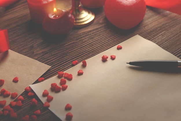 Tarjeta de regalo para el Día de San Valentín con bolígrafo y velas sobre fondo de madera