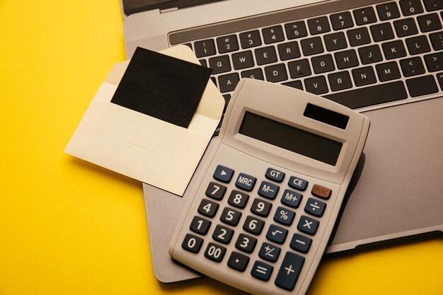 Tarjeta en un sobre artesanal teclado portátil y calculadora sobre un fondo amarillo