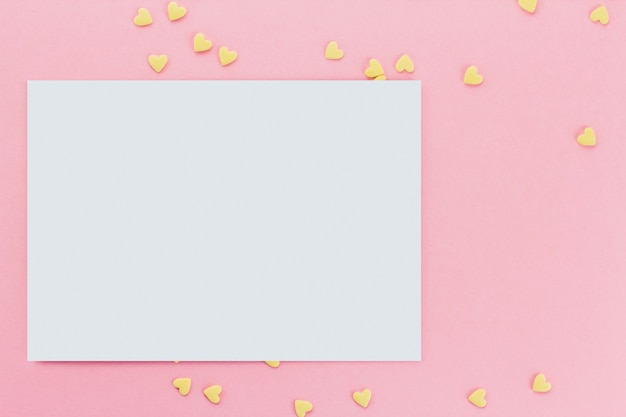 Tarjeta sobre un fondo de confeti de confitería en forma de corazón sobre un fondo rosa copia espacio. Corazones amarillos