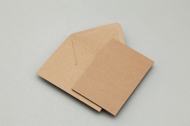 Tarjeta y sobre de papel kraft marrón en blanco sobre un fondo gris