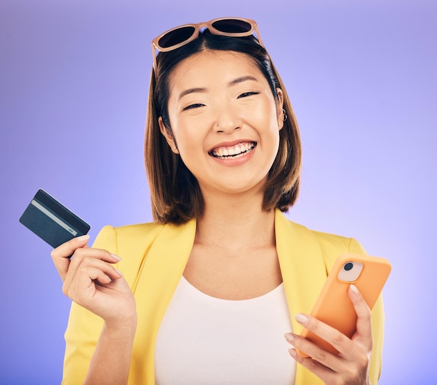 Tarjeta de teléfono celular y retrato de una mujer en el estudio para compras en línea en el sitio web de comercio electrónico Sonrisa feliz y modelo femenino asiático con banca por Internet para pagar facturas con teléfono de fondo morado