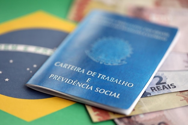 Tarjeta de trabajo brasileña y libro azul de seguridad social y billetes de dinero en reales con bandera federativa