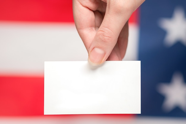 Foto tarjeta vacía en mano de mujer con fondo de bandera americana