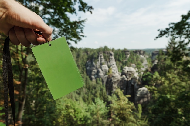 Tarjeta verde en manos de los hombres en el fondo del Parque Nacional de Suiza Sajona, Alemania.