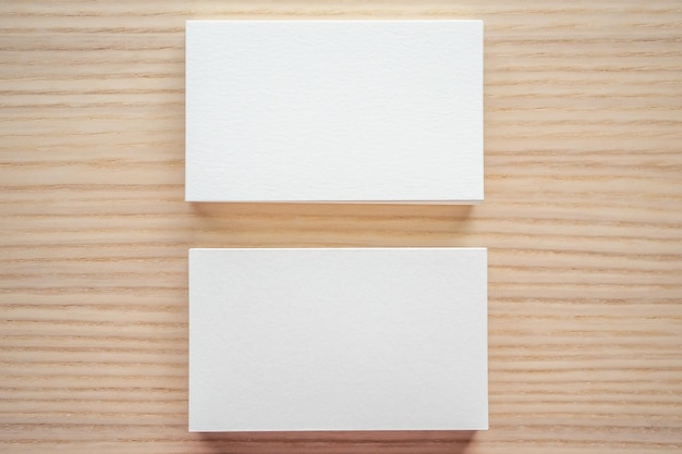 Tarjeta de visita blanca sobre fondo de mesa de madera