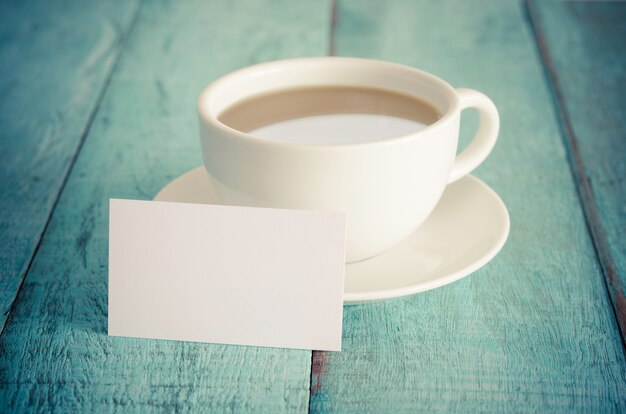 Tarjeta de visita en blanco y taza de café en la mesa de madera azul.