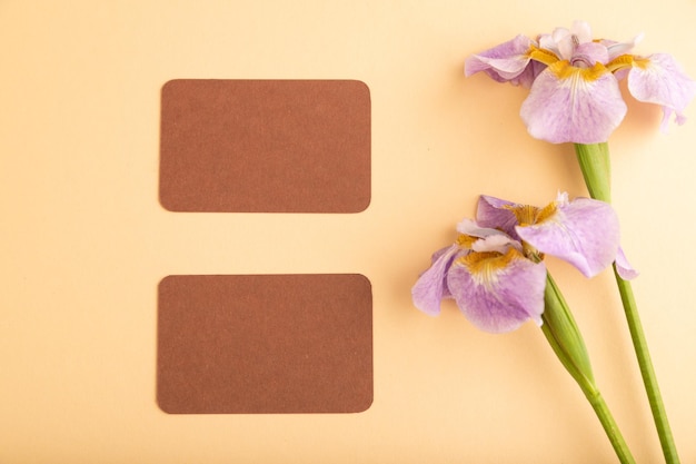 Tarjeta de visita marrón con flores de iris lila sobre fondo naranja pastel espacio de copia de vista superior