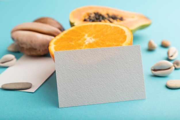 Tarjeta de visita de papel blanco con conchas de papaya naranja cortadas maduras sobre fondo azul pastel Vista lateral de cerca