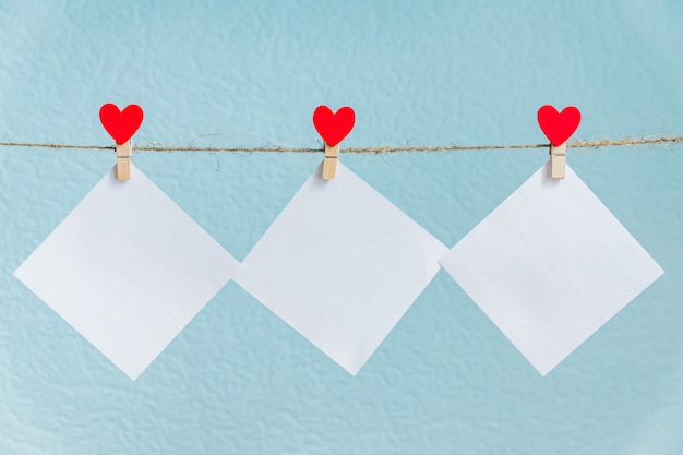 Tarjetas en blanco en alfileres con corazones rojos. texto y fondo azul para saludos del día de San Valentín