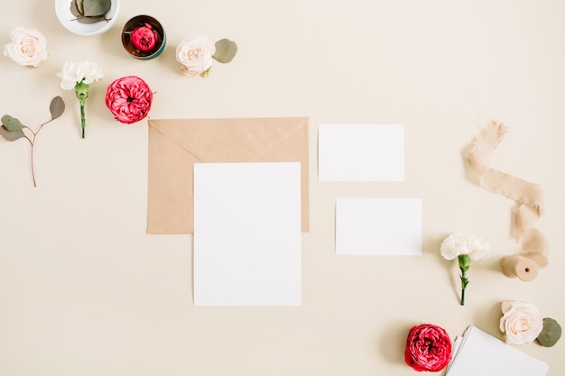 Tarjetas de invitación de boda, sobres artesanales, capullos de rosas rosadas y rojas y clavel blanco sobre beige pastel pálido