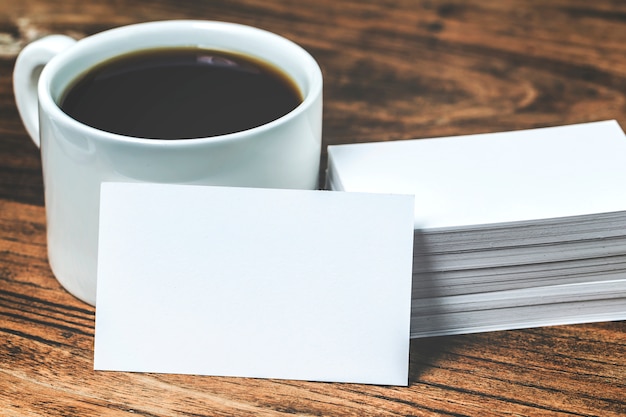 Tarjetas de visita en blanco y taza de café en la mesa de madera. Corporativa de marca estacionaria simular.