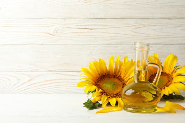 Tarro de aceite de girasol y vidrio sobre mesa de madera blanca