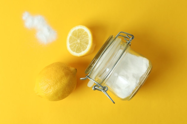 Tarro de ácido en polvo y limones sobre fondo amarillo aislado
