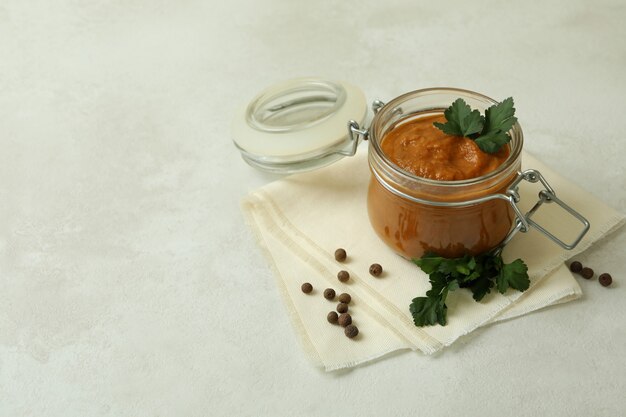 Tarro con caviar de calabacín en mesa con textura blanca