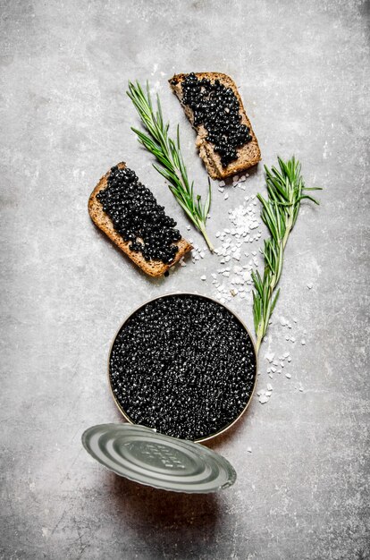 Tarro con caviar negro y bocadillos en la mesa de piedra