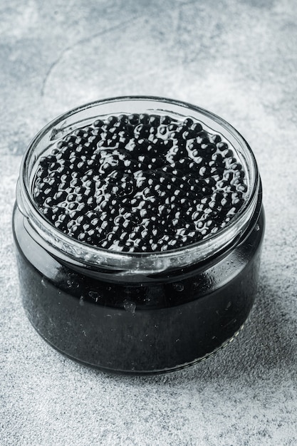 Foto tarro de caviar negro, sobre mesa gris