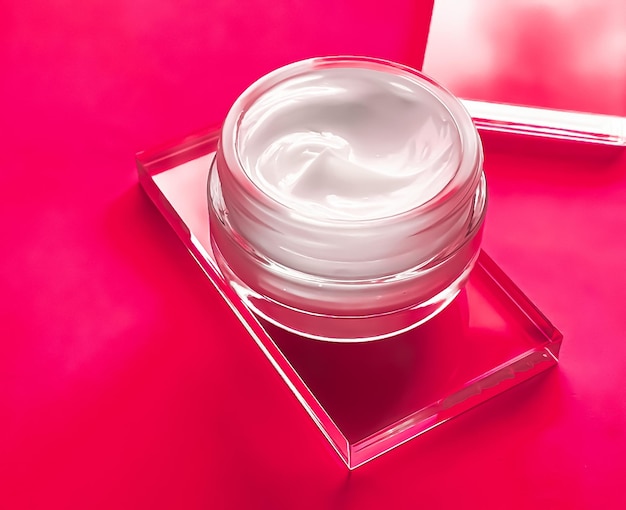 Tarro de crema hidratante para la cara sobre vidrio y fondo rosa producto de belleza y ciencia cosmética para el cuidado de la piel