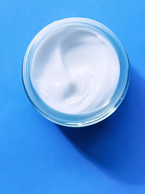 Tarro de crema hidratante facial como muestra de producto sobre fondo azul belleza y ciencia cosmética para el cuidado de la piel