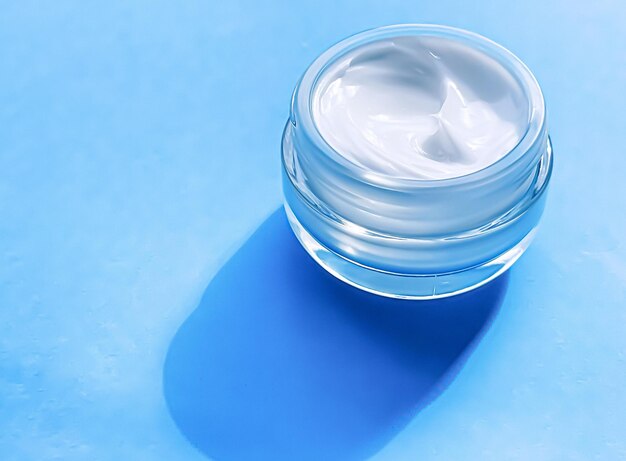 Tarro de crema hidratante facial como muestra de producto sobre fondo azul belleza y ciencia cosmética para el cuidado de la piel