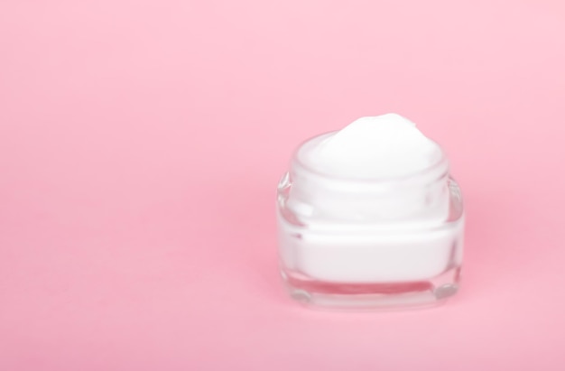 Tarro de crema hidratante facial sobre fondo rosa loción hidratante para el cuidado de la piel y cosméticos antiedad de emulsión para la marca de cuidado de la piel de belleza de lujo