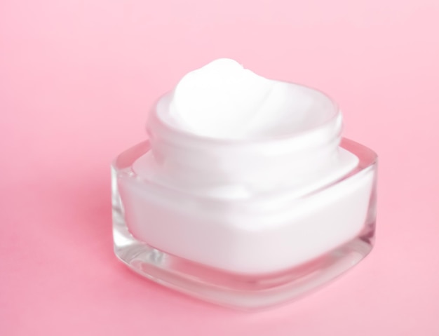 Tarro de crema hidratante facial sobre fondo rosa loción hidratante para el cuidado de la piel y cosméticos antiedad de emulsión para la marca de cuidado de la piel de belleza de lujo