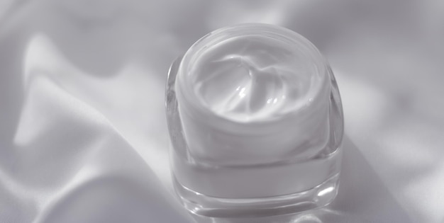 Tarro de crema hidratante facial sobre fondo de seda loción hidratante para el cuidado de la piel y cosméticos antiedad de emulsión para la marca de cuidado de la piel de belleza de lujo