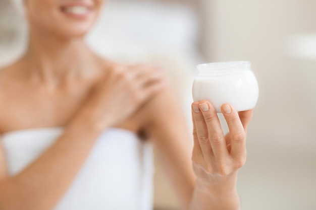 Tarro con crema en mano de mujer desnuda irreconocible