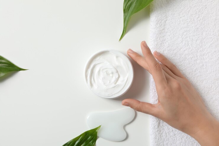 Un tarro de crema de manos con hojas sobre un fondo claro.