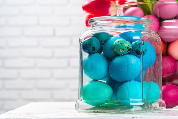 Tarro de cristal con huevos de colores brillantes para la celebración de Pascua