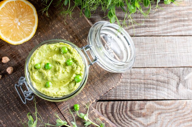 Tarro de cristal de hummus verde, deliciosa crema de garbanzos y guisante verde