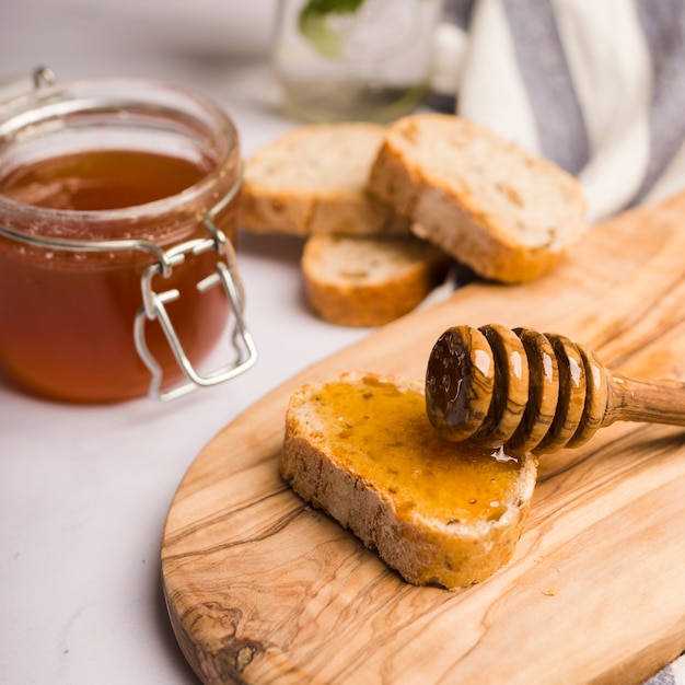 Foto tarro de cristal lleno de miel con cuchara de miel