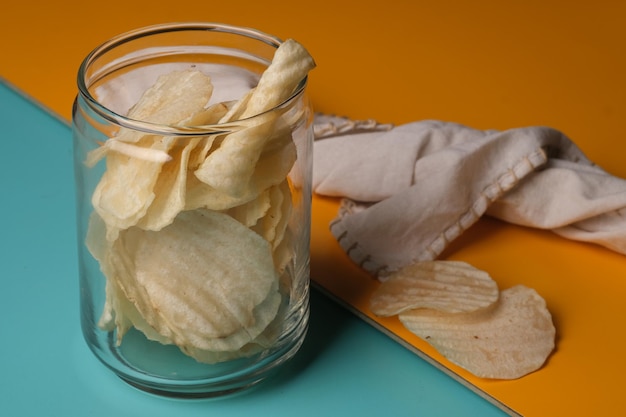 Un tarro de cristal de patatas fritas se asienta sobre un mantel amarillo y naranja.