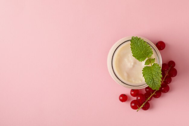 Tarro de cristal de yogur de crema agria y arándano sobre fondo rosa