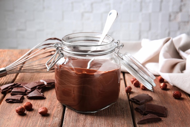 Tarro con deliciosa salsa de chocolate sobre mesa de madera