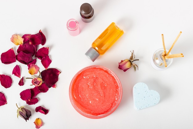 Tarro de exfoliante facial cosmético con pétalos de rosa y aceites esenciales. Cosméticos orgánicos. Salón de spa, cuidado de la piel