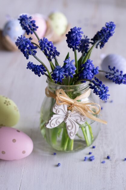 Un tarro de flores con huevos de pascua sobre la mesa