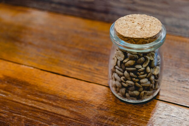 Tarro de granos de café tostados en la mesa de madera